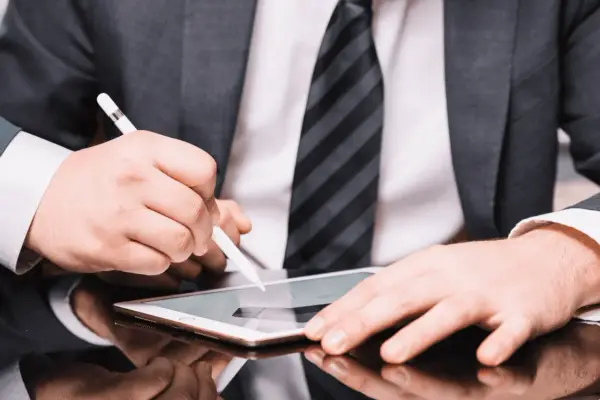 Hombre con traje firma un contrato con certificado digital en una tablet.