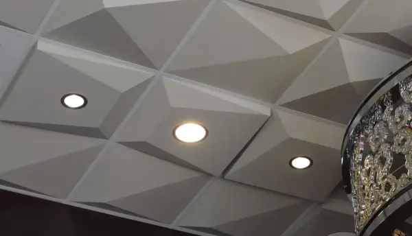 Nowoczesny sufit z geometrycznymi panelami i wbudowanymi punktami świetlnymi. Świetna alternatywa dla kasetonów, nadająca wnętrzu charakteru.
