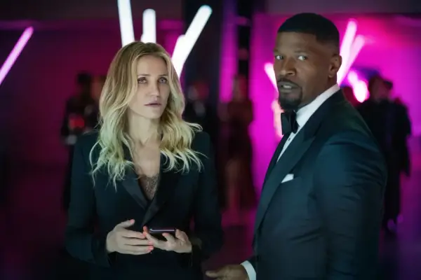 Cameron Diaz i Jamie Foxx znowu w akcji, w eleganckich strojach, na tle neonowych świateł.