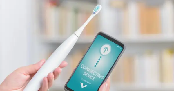 Ręka trzyma białą szczoteczkę elektryczną i smartfon z napisem "CONNECTING DEVICE". Czy mogę wziac szczoteczke elektryczna do samolotu?