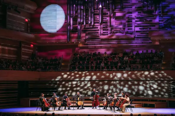 Un orchestre joue sur scène, éclairé par une lune projetée. C'est quoi un single ? Une pièce musicale unique, comme un solo d'un musicien.