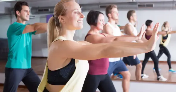 Ludzie na zajęciach zumbą, uśmiechnięci, wykonują ruchy. Zumbę co daje? Radość, energię i świetną sylwetkę!