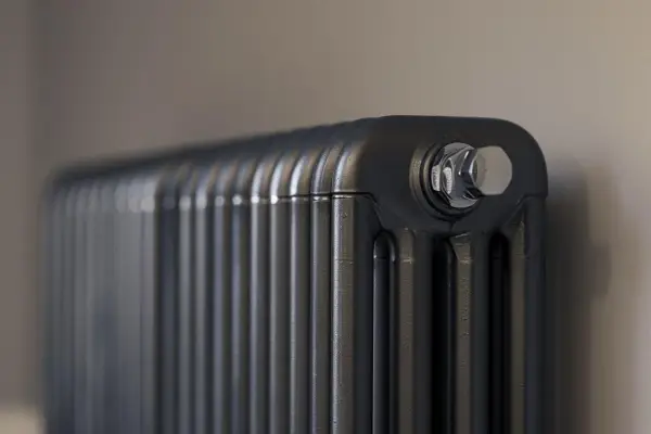 Gros plan sur un radiateur bain d'huile noir, avec un bouchon chromé visible. Un élément clé pour gérer la consommation d'énergie.