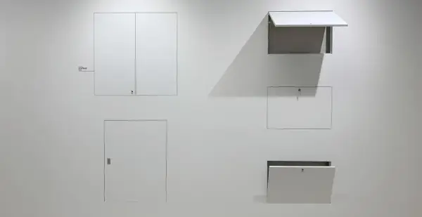 Botole cartongesso invisibili filo muro, integrate perfettamente nella parete bianca, alcune aperte, altre chiuse, nascondono accessi segreti.