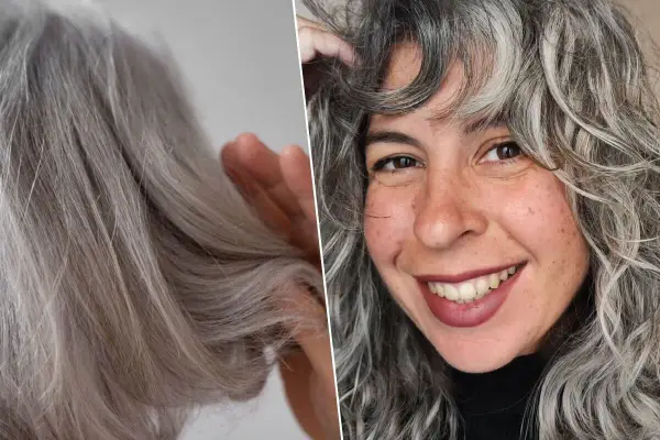 Una mujer sonríe mostrando su cabello con canas, que luce rizado y con mechones plateados.