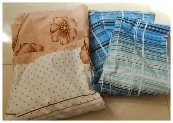 Tissus pliés, un à fleurs beiges et pois, l'autre à rayures bleues. Idéal pour apprendre comment faire un drap housse.