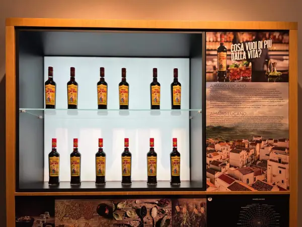 Butelki amaro Lucano stoją na półkach, tworząc elegancką ekspozycję.