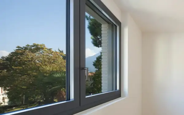Finestra in alluminio con vista su alberi e montagne. Utile per chi cerca come regolare vecchi infissi in alluminio.