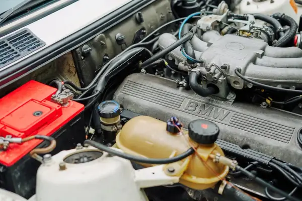 Silnik BMW 1.6 mpi z widocznym akumulatorem i zbiorniczkiem płynu.