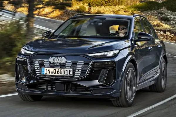Ciemnogranatowy Audi Q6 e-tron jedzie po krętej drodze. Sprawdź atrakcyjną audi q6 e-tron cenę.