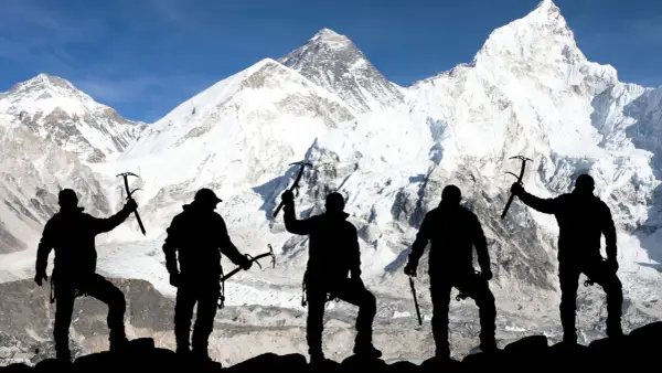 Pięciu alpinistów z czekanami na tle ośnieżonego Mount Everestu. To symboliczne przedstawienie, bo ile osób weszło na Mount Everest, to już inna historia.