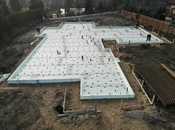 Budowa fundamentów z płyt izolacyjnych i zbrojenia. Szybki beton wkrótce zaleje tę konstrukcję, tworząc solidną podstawę.