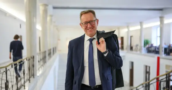 Uśmiechnięty mężczyzna w garniturze, który może być powiązany z pytaniem, dlaczego Robert Telus i Rafał Romanowski zostali zawieszeni w prawach członka.