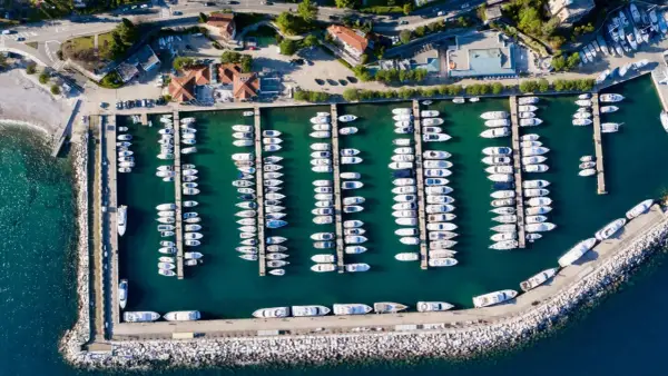 Widok z lotu ptaka na port w Chorwacji, pełen białych jachtów i łodzi zacumowanych w turkusowej wodzie.