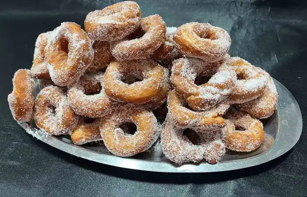 Montón de buñuelos de cuaresma espolvoreados con azúcar, listos para disfrutar.
