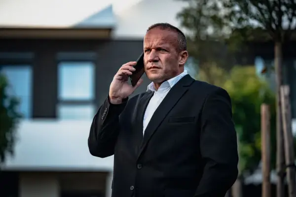 Krzysztof Bukowski, reżyser, w garniturze rozmawia przez telefon.