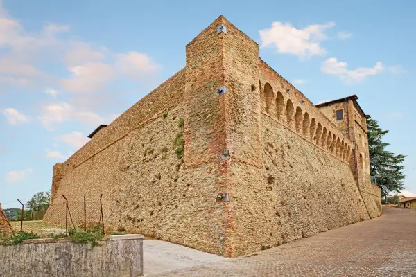 Antica fortezza nella valle del Rubicone, con mura in pietra e mattoni, torri e un loggiato ad archi.
