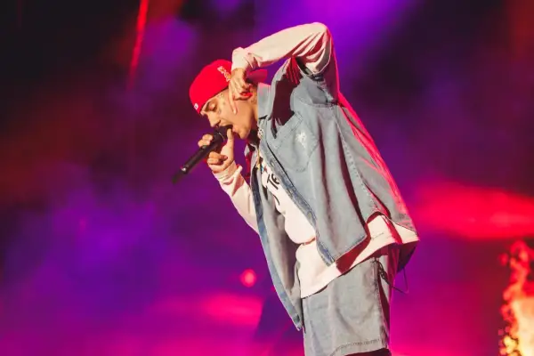 Un artista con gorra roja y ropa vaquera canta en un concierto boombastic Asturias.