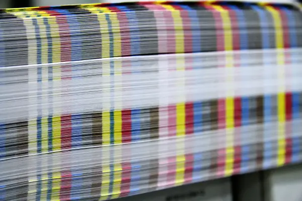 Kolorowe paski CMYK na krawędziach papieru świadczą o pracy w branży poligraficznej.