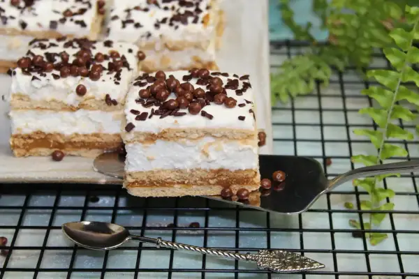 Pyszne ciasto Trzy Bit z kremem i czekoladowymi posypkami, serwowane na łopatce.