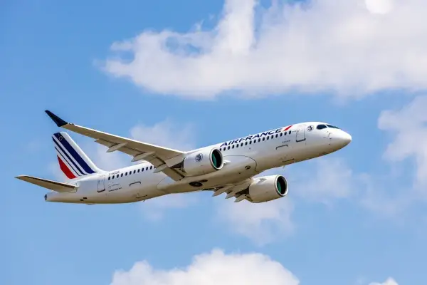 Airbus A220-300 linii Air France wzbija się w błękitne niebo z białymi chmurami.