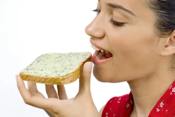 En kvinna med gluten mage njuter av en smörgås med örtsmör.