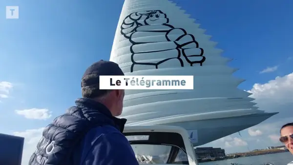 Un homme regarde une voile géante ornée du logo Michelin. Le Télégramme est affiché sur la voile.