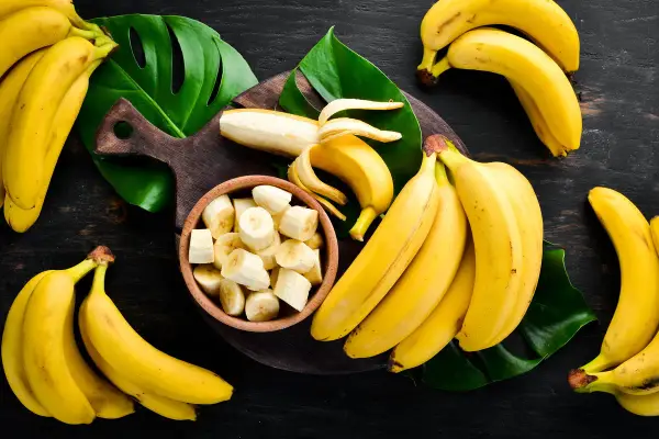 Pęki dojrzałych bananów, jeden obrany i pokrojony w miseczce. Zastanawiasz się, ile węglowodanów ma banan?