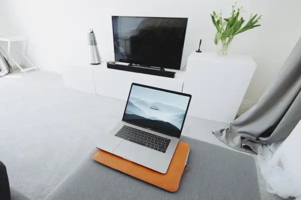 Nowoczesny salon z laptopem przygotowanym do screen mirroring na dużym ekranie telewizora.