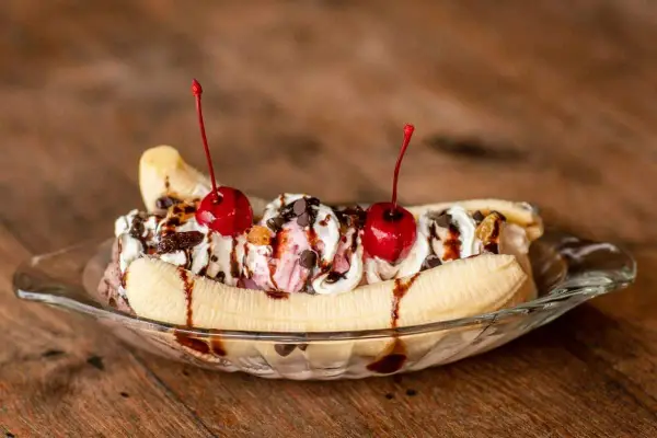Un déliceux banana split avec glace, crème fouettée, pépites de chocolat et cerises. Une recette parfaite pour un dessert gourmand.