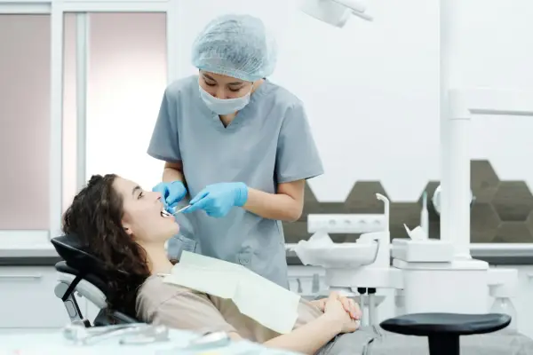Dentystka bada zęby pacjentki, szukając oznak problemów, które mogą wymagać leczenia kieszonek dziąsłowych.