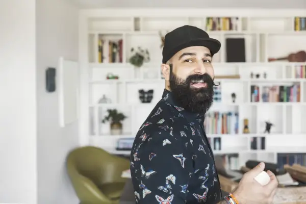 Ein lächelnder Mann mit Bart und Kappe, der als creative director neue Ideen entwickelt.
