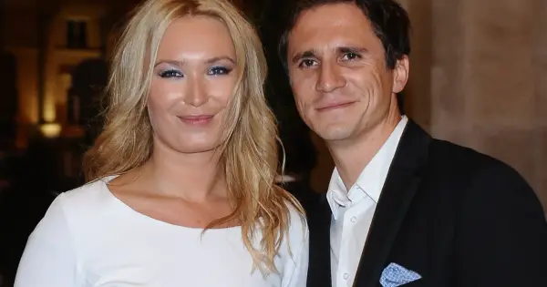 Uśmiechnięta para, być może rodzice Sambora Czarnoty, pozuje do zdjęcia. Kobieta ma blond włosy i białą sukienkę, mężczyzna czarny garnitur.