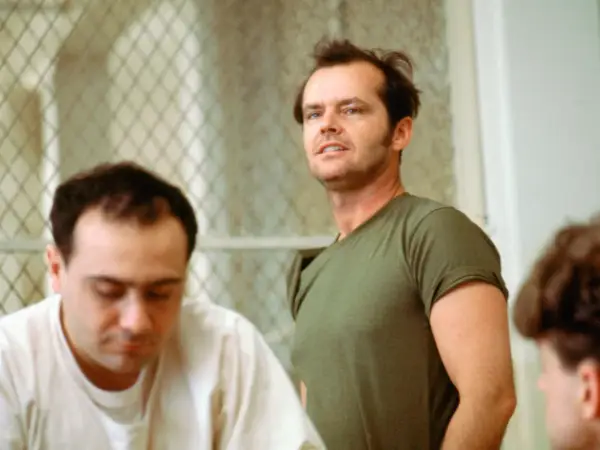 Jack Nicholson, con sguardo intenso, incarna la ribellione nel film "Qualcuno volò sul nido del cuculo", sfidando l'autorità in un contesto di reclusione.