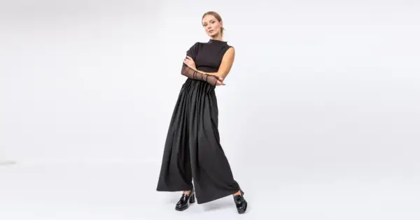 Elegancka stylizacja do teatru: czarny top z siateczkowymi rękawami i szerokie spodnie z wysokim stanem.