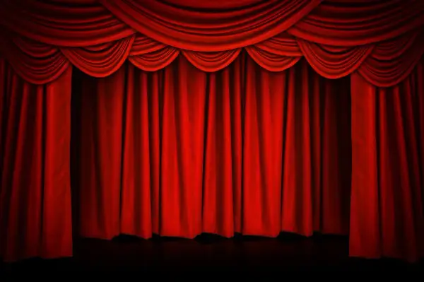 Czerwona, teatralna kurtyna w teatrze, z bogatymi drapowaniami u góry, gotowa do odsłonięcia sceny.