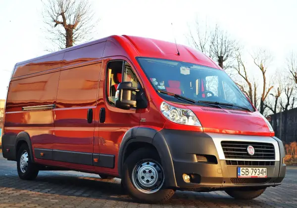 Czerwony Fiat Ducato Maxi zaparkowany na zewnątrz, gotowy do transportu.