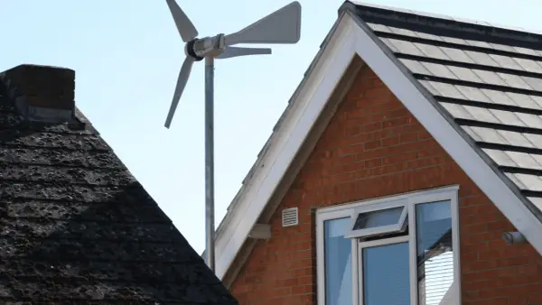 Une petite éolienne maison capte le vent au-dessus des toits.