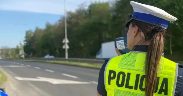 Policjantka w kamizelce odblaskowej mierzy prędkość pojazdów. Uważaj na tryb przyspieszony na drodze!
