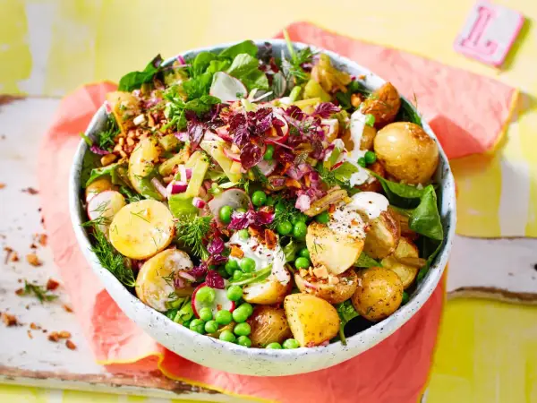 Kartoffelsalat mal anders: Ein bunter Mix aus kleinen Kartoffeln, Erbsen, Radieschen, Zwiebeln und Kräutern in einer Schüssel.