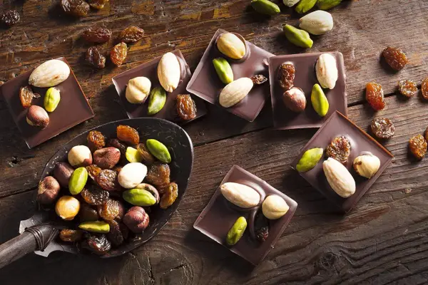 Carrés de chocolat noir Callebaut garnis d'amandes, noisettes, pistaches et raisins secs. Un délice à déguster !