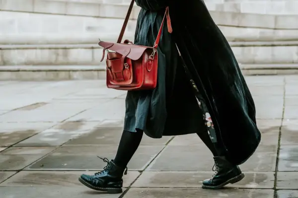 Czarne martensy i czerwona torba tworzą stylowy zestaw. Długa, czarna sukienka dodaje elegancji.