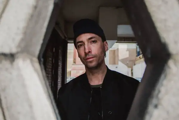 Tim Hecker, artiste sonore, regarde à travers une structure architecturale.