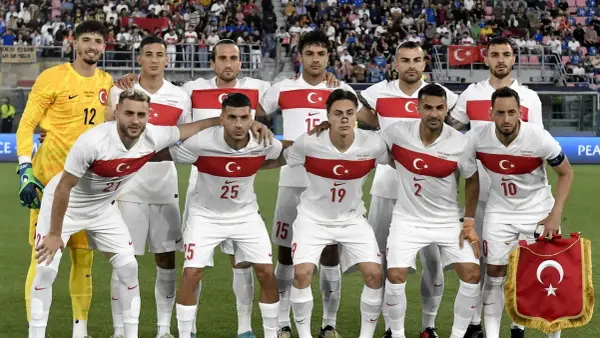 Piłkarze reprezentacji **turcja fc** w białych strojach z czerwonym pasem i godłem. Bramkarz w żółtym.