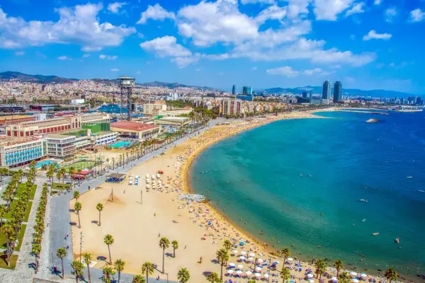 Vista aérea de la playa de la Barceloneta, una de las mejores playas de Barcelona, con gente disfrutando del sol y el mar Mediterráneo.
