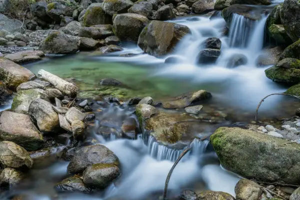 Acqua cristallina scorre tra rocce muschiose, creando un effetto seta su un ruscello di montagna.