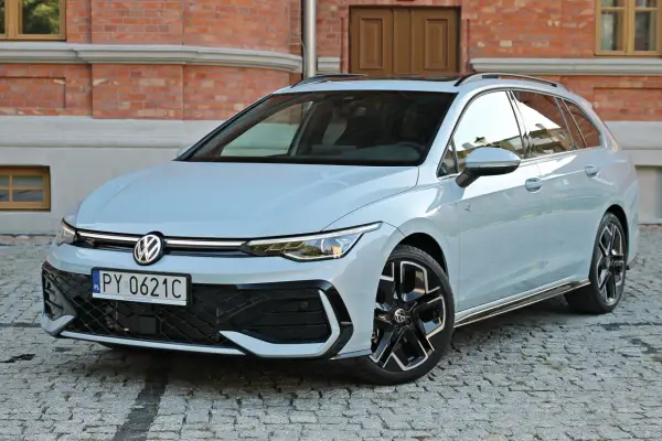 Jasny VW Golf 8 Variant na brukowanej ulicy przed ceglanym budynkiem. Elegancki kombi z nowoczesnym designem.