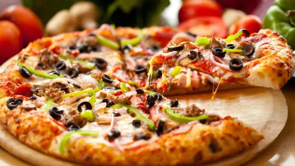 Gotowe ciasto na pizzę z mnóstwem dodatków: pepperoni, oliwki, papryka, cebula i ser. Idealne na wieczór filmowy!