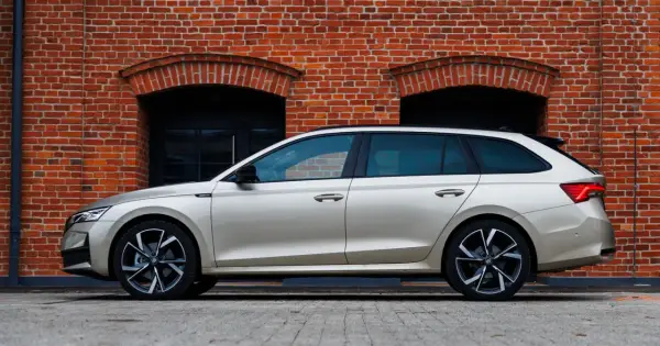 Złoty kombi Octavia 4 stoi na tle ceglanej ściany z dwoma łukowatymi oknami.