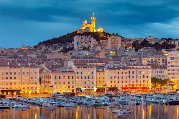 Il porto di Marsiglia MSC, con le luci della città e la basilica di Notre-Dame de la Garde in cima alla collina, crea uno scenario suggestivo al crepuscolo.